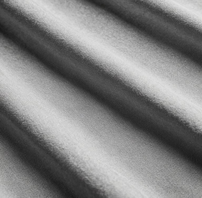 Extreme close-up of heavy 480gsm loopback cotton fabric texture, showing the intricate structural weave, high-contrast studio lighting, desaturated black and white