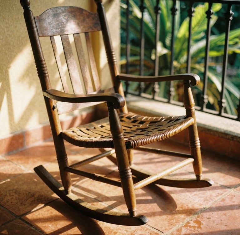 Close-up of a traditional rocking chair on terracotta tiles, warm golden-hour light filtering through colonial iron grilles, soft shadows, 35mm film style