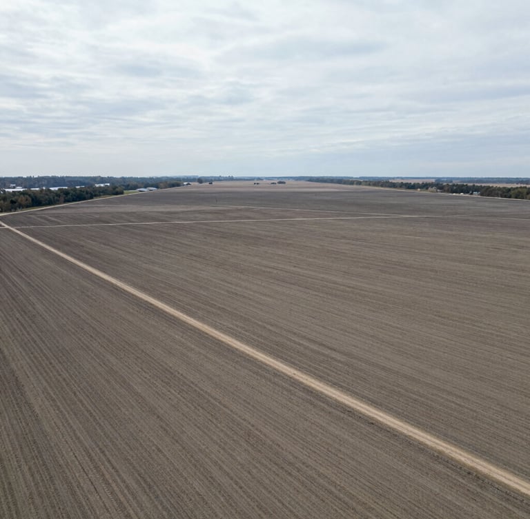 High-altitude aerial drone shot of a raw land parcel boundary, natural overcast daylight, realistic desaturated tones, sharp borders, 35mm