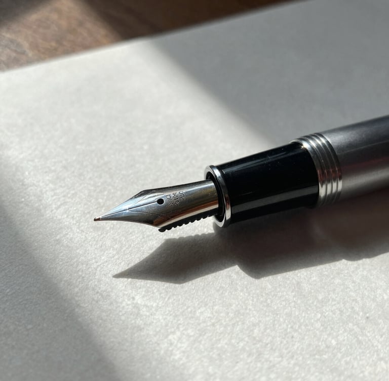 Close-up macro shot of a high-quality fountain pen resting on heavy textured cotton paper. Overcast natural light from a side window, dramatic architectural shadows.