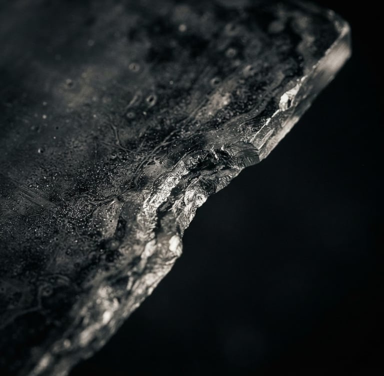 Extreme macro shot of a wet-plate glass edge, rich silver tones, dramatic low-key side lighting, deep charcoal background.