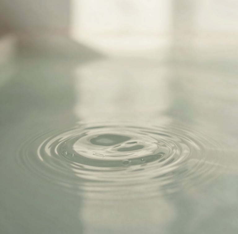 Macro shot of gentle ripples in clean water, soft natural daylight, calming sage and off-white tones, shallow depth of field, 35mm