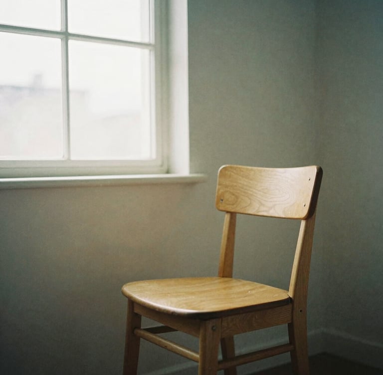Quiet studio interior with a single oak chair, soft north-facing daylight filtering through a window, muted beige and dusty blue tones, 35mm film texture.