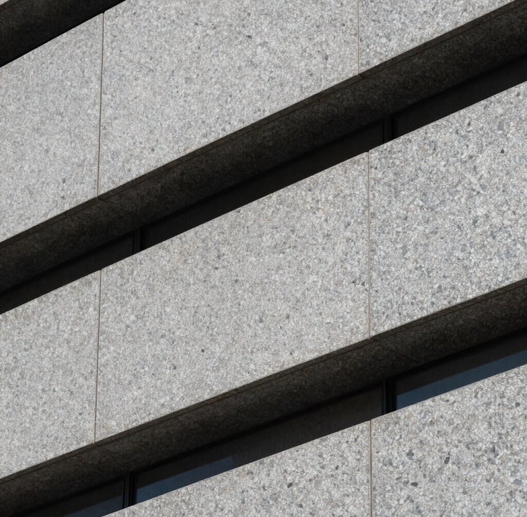 Abstract close-up of a modern granite building facade, clean sharp shadows, architectural lines, cool stone gray tones.