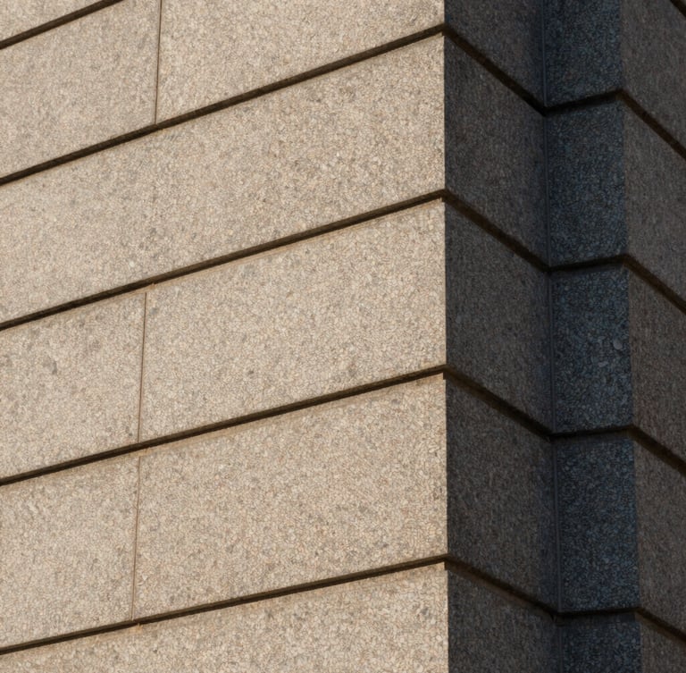 Abstract architectural close-up of a granite building facade in Cheyenne, sharp clean stone lines, subdued morning light.