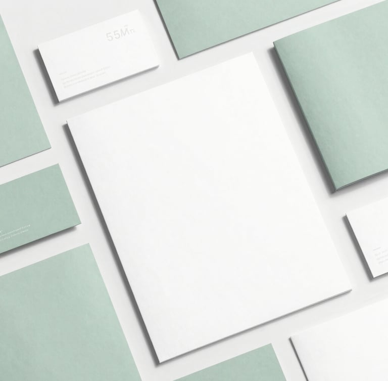 High-quality flat-lay of elegant printed brand collateral (business cards, letterhead, brochures) with subtle sage green accents, minimalist composition, bright natural daylight, 35mm