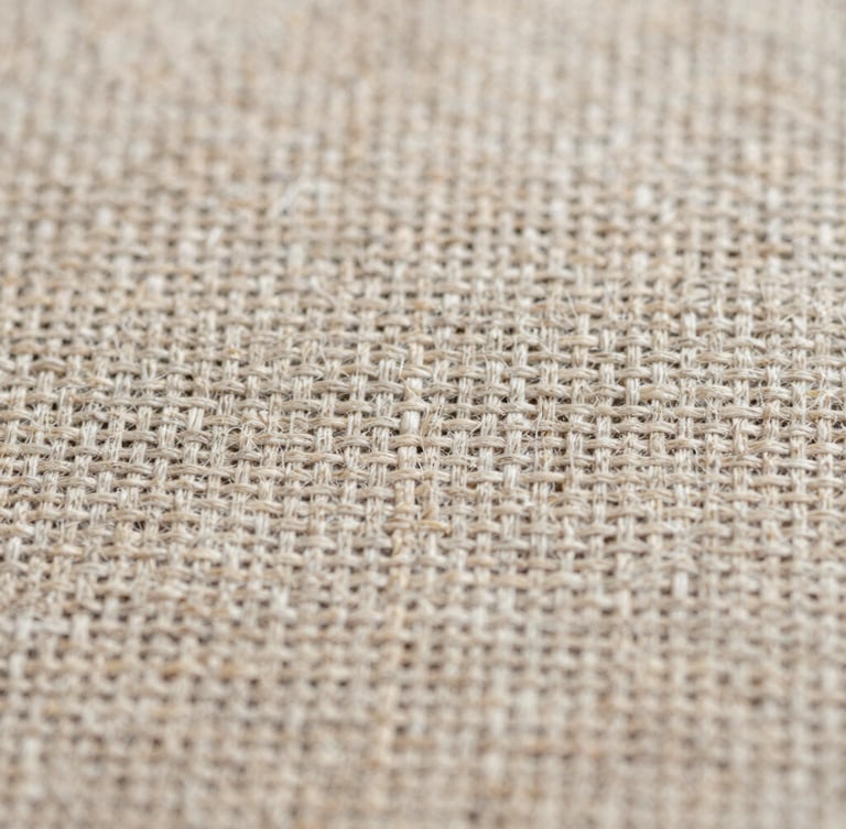 Extreme macro close-up of raw linen fabric weave, showing high-detail warp and weft fibers under soft, diffused daylight, neutral earth tones, 35mm