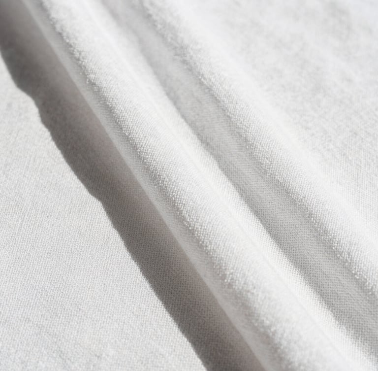 Extreme close-up of a premium white linen fabric weave, showing the rich organic texture and cross-hatched threads under bright direct sunlight with sharp shadows.