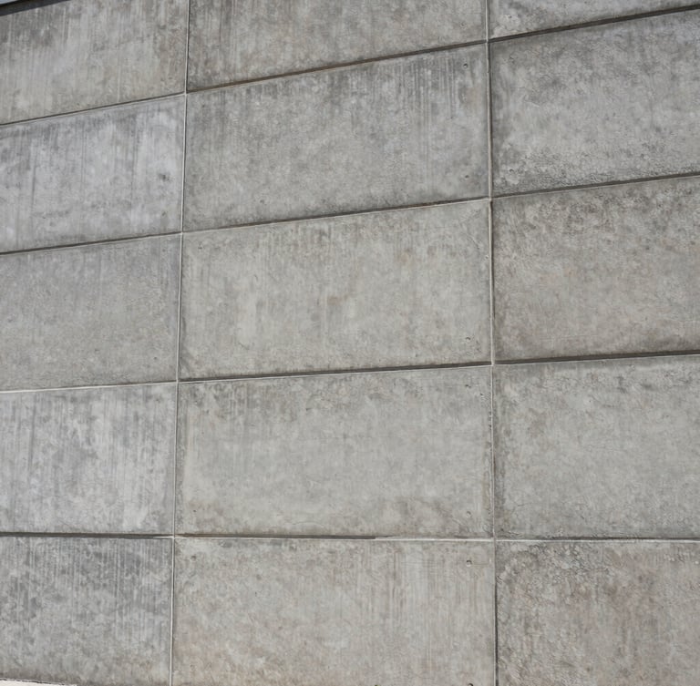 Low-angle architectural shot of a massive concrete retaining wall, uniform gray tone, industrial aesthetic, high-contrast daylight