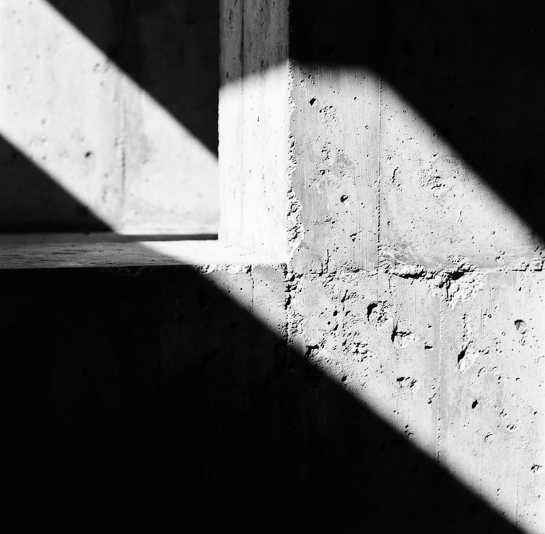 Extreme close-up of sharp architectural concrete shadows under harsh directional sunlight, high contrast black and white, minimalist composition, 35mm film grain