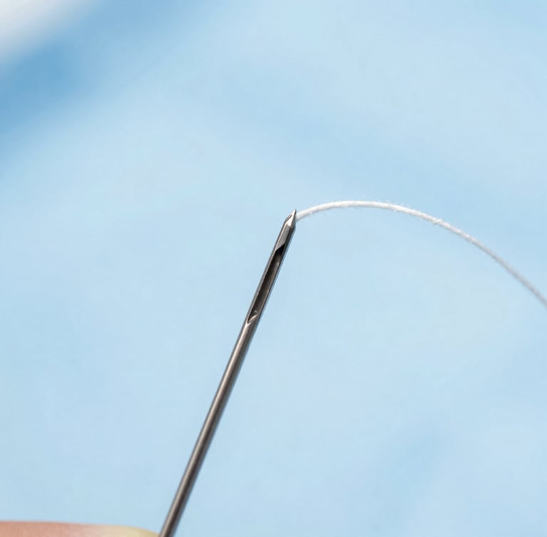 Macro photography of sterile surgical suture thread threaded through a precision curved needle, cool clinical lighting, sterile blue background.