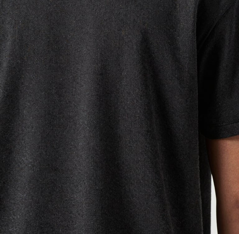 Close-up of premium fabric texture on a dark grey t-shirt, highlighting precise stitching and high-quality weave, moody studio lighting