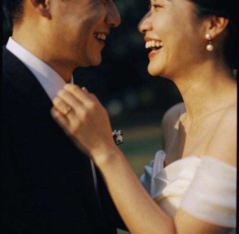 Intimate candid shot of a couple laughing, motion blur on their hands, warm golden light, rich shadows, 35mm film grain