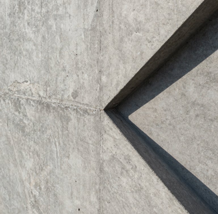 Extreme close-up of a flawless exposed concrete wall, sharp geometric shadows cast by natural sunlight, showing the raw tactile texture and perfect formwork joints.