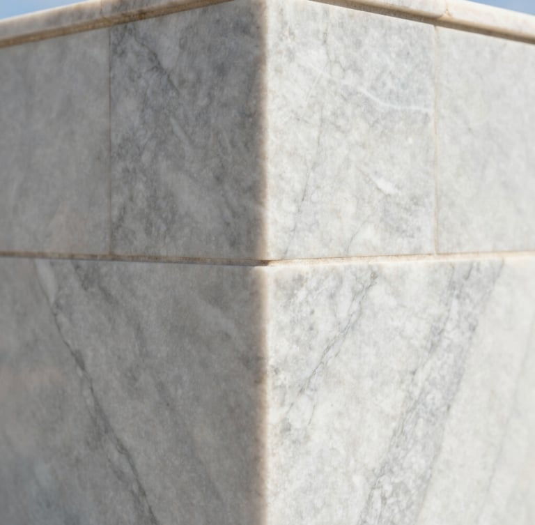 Extreme close-up of a perfectly mitered corner of large-format Calacatta marble in bright coastal daylight, showing zero-tolerance alignment and crisp details