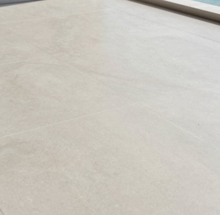 Architectural close-up of a perfectly level substrate with laser alignment lines projected across a large-format porcelain tile installation, soft natural coastal light, pale sage and sand tones, crisp detail, 35mm