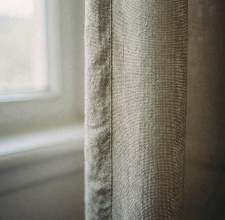 Tactile editorial photography of an extreme close-up of raw heavy-weight flax edges, showing detailed thread texture and weft and warp, soft morning window light, muted earthy tones, 35mm film