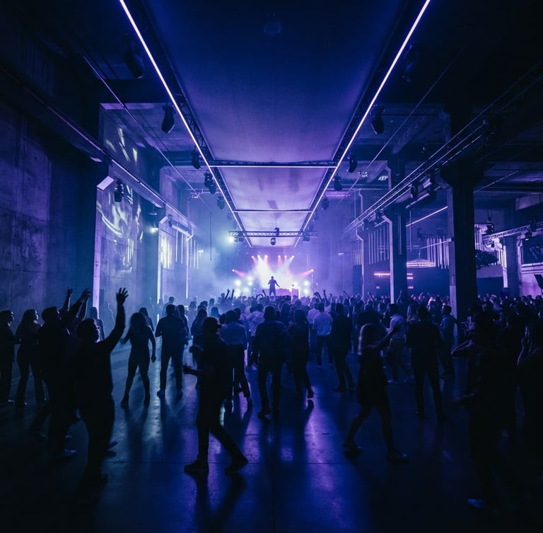 Wide panoramic shot of an immersive event space, dramatic architectural lighting in deep indigo and electric violet, silhouettes of guests in motion, high-contrast and moody ambient light, cinematic lens.