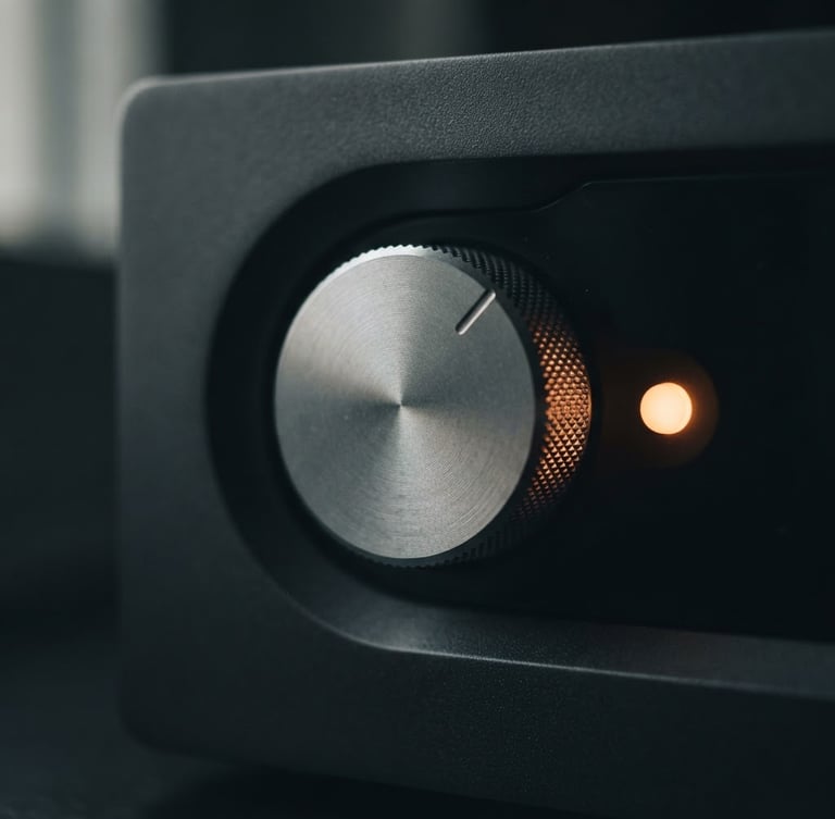 Macro close-up of a machined aluminum dial on a dark obsidian hardware device, soft orange indicator light glowing, low-key side window lighting, shallow depth of field