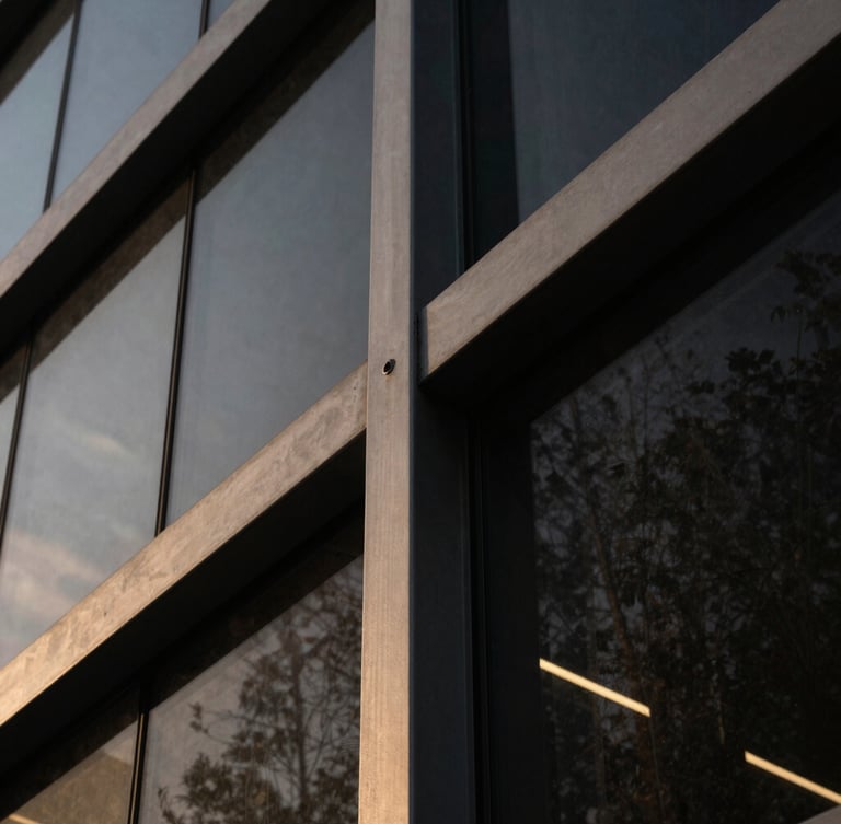 Extreme close-up of architectural steel and dark glass angles, dramatic low-key lighting with subtle golden reflections, clean minimalist composition.