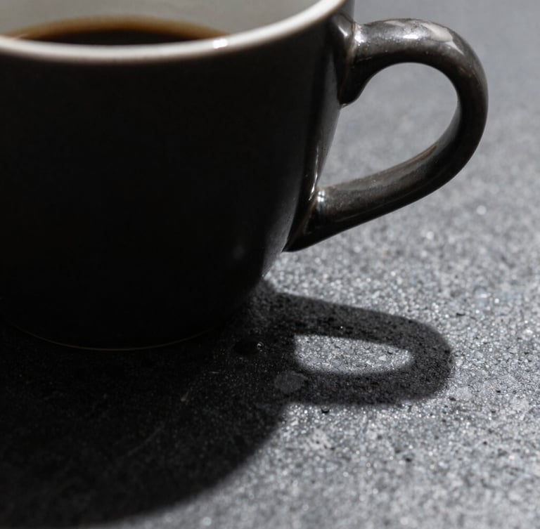 Macro close-up of a sleek dark ceramic espresso cup on an obsidian stone desk, dramatic side lighting, deep sharp shadows, premium minimalist aesthetic