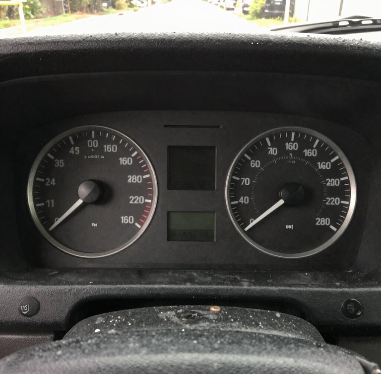 Close-up of a transit bus dashboard instrument cluster, sharp focus on dials and digital readout, early morning garage lighting, natural gritty colors