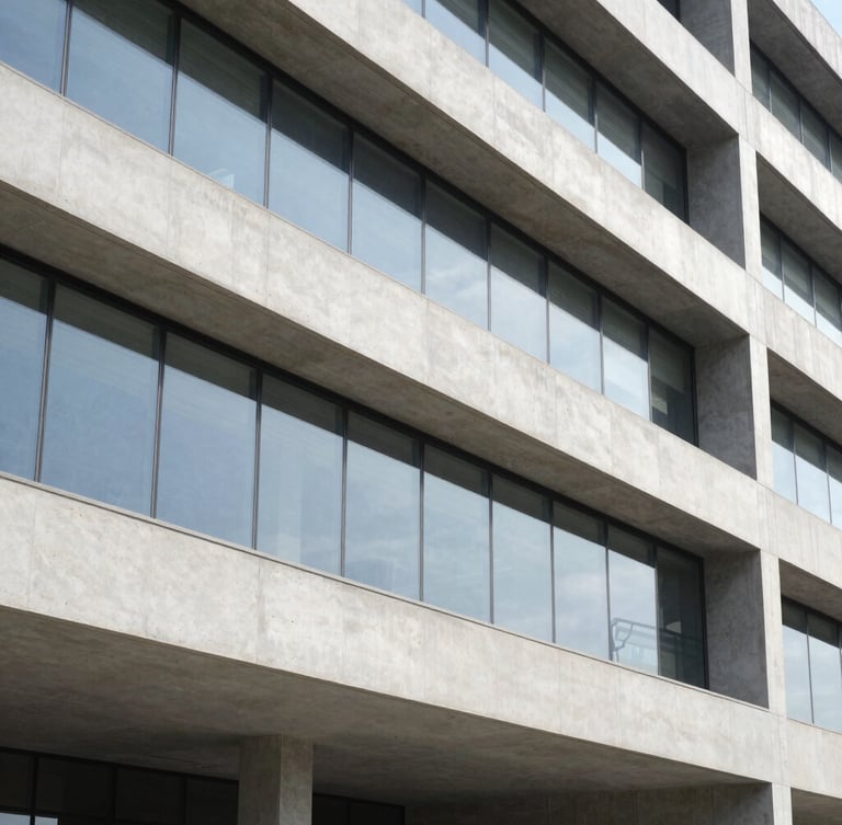 Detalhe arquitetônico de uma estrutura de concreto polido e vidro, com reflexos geométricos, sob luz natural nítida, enquadramento vertical.