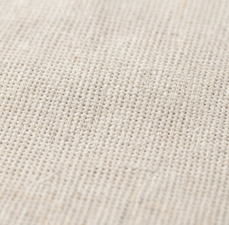 Macro close-up of raw linen fabric showing detailed weave and thread count under clean, natural daylight, high-contrast texture