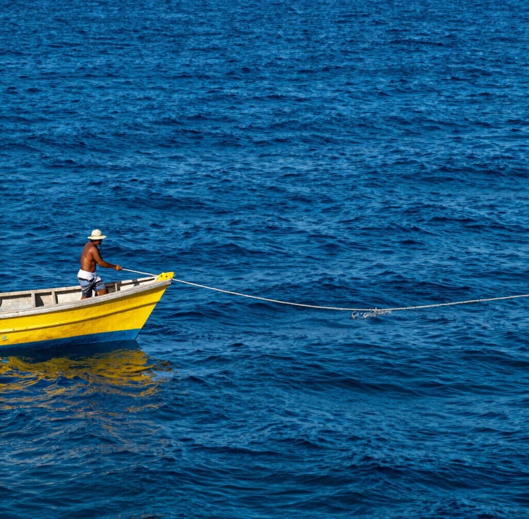 A local fisherman on a small wooden vessel pulling a thick handline from deep blue water, harsh tropical sunlight, sharp focus
