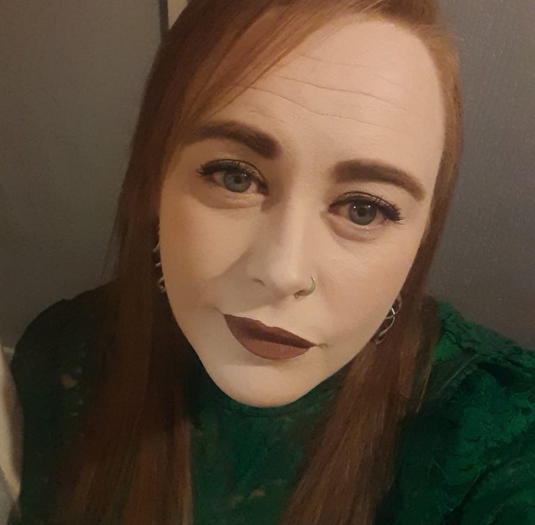 Nicola, wearing a green lace top and dark lipstick.