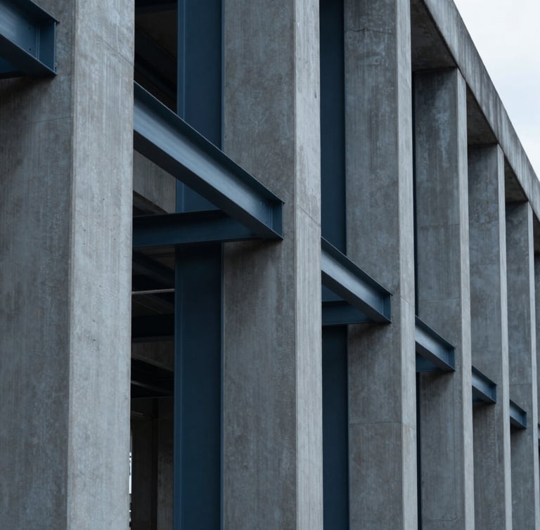 Low-angle architectural perspective of structural steel and concrete pillars, sharp shadows, cool overcast daylight, deep slate tones