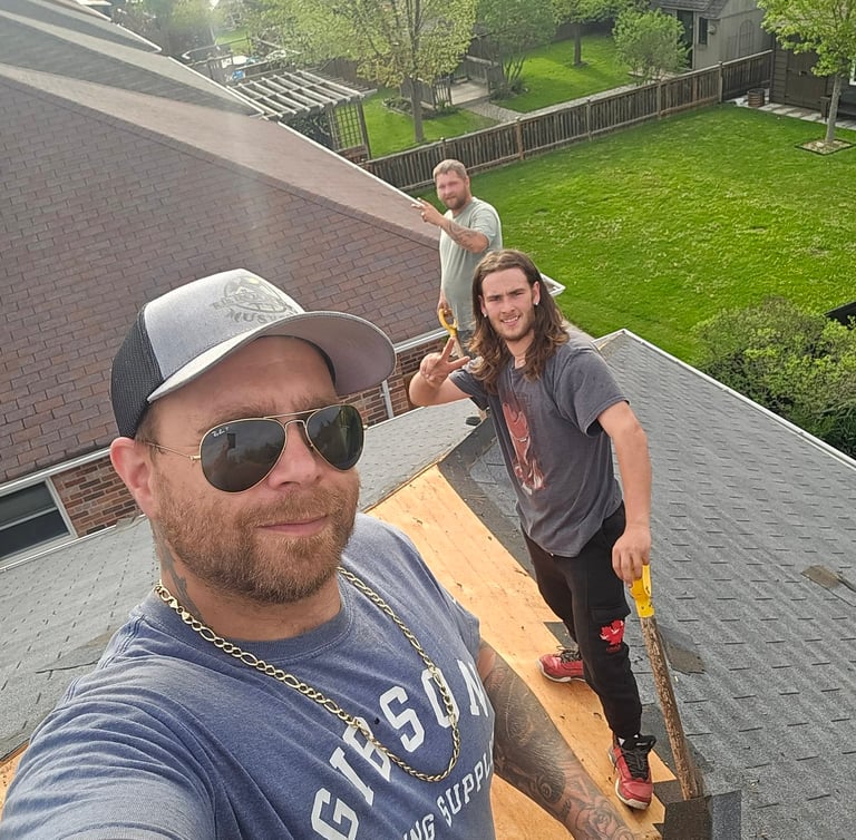Professional roofing contractors removing old asphalt shingles during a residential roof replacement project.