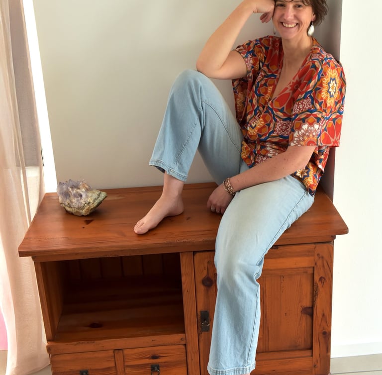 julie mansencaut sitting on a wooden bench with a bookcase