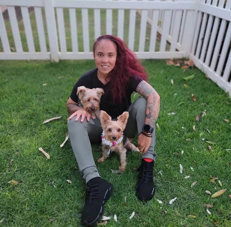 a woman sitting on the grass with two dogs