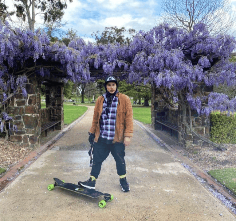 Kasaysayan DTC First Writer Match Makata Cassidy holding a skateboard, park, font of wisterias 