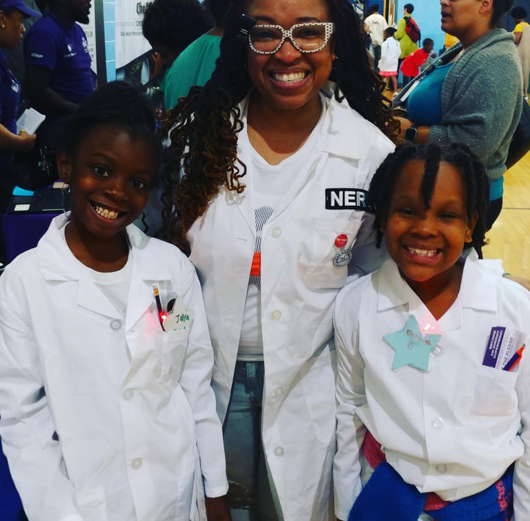 Shenell poses with two young scholars. All three are in labcoats