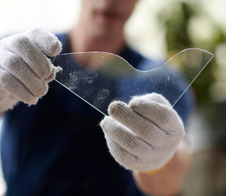 Technician handling shower glass panel with safety gloves