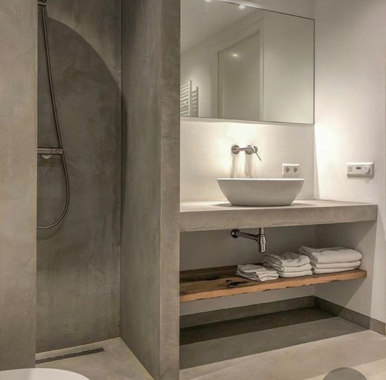 Modern industrial bathroom featuring a microcement walk-in shower and floating concrete vanity with a vessel sink.