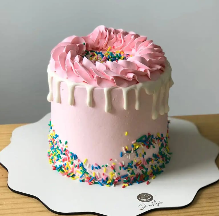 Bolo decorado com glacê rosa e confeitos coloridos, perfeito para festas e celebrações. Uma delícia