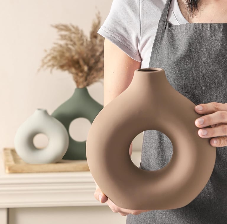 A person holding a brown ceramic donut vase featuring a minimalist nordic style for home decor.