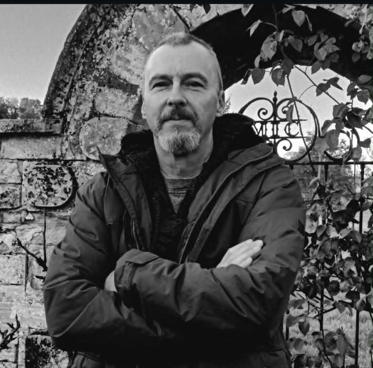 The author Jon Clynch standing by a stone arch with wrought iron gate