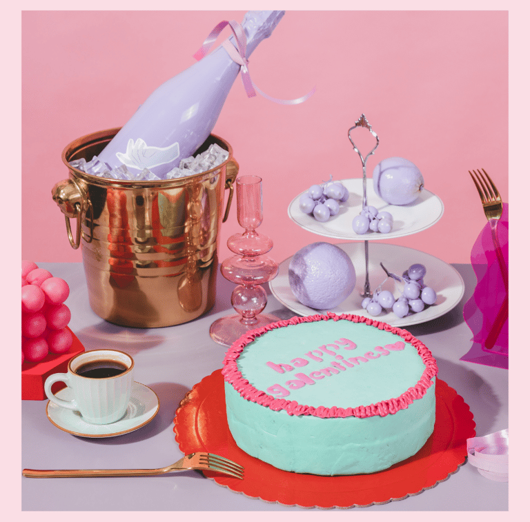 Galentines Day Party table decorated with a cake, a champagne bottle, coffee and goodies.