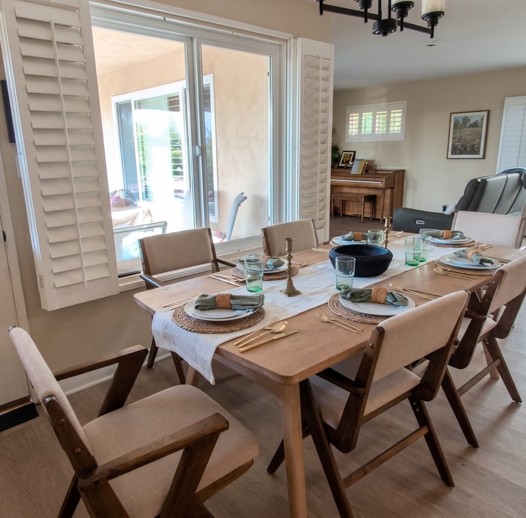 Modern wooden dining table set with mid-century chairs in a bright, open-concept home interior.