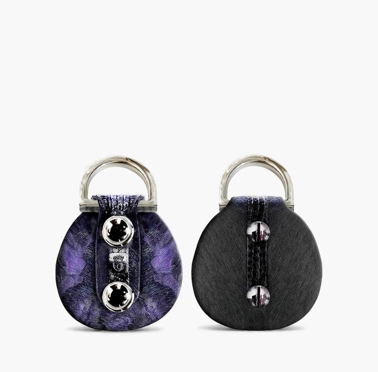 Two circular designer key rings featuring purple marble and black textured finishes with silver hardware.