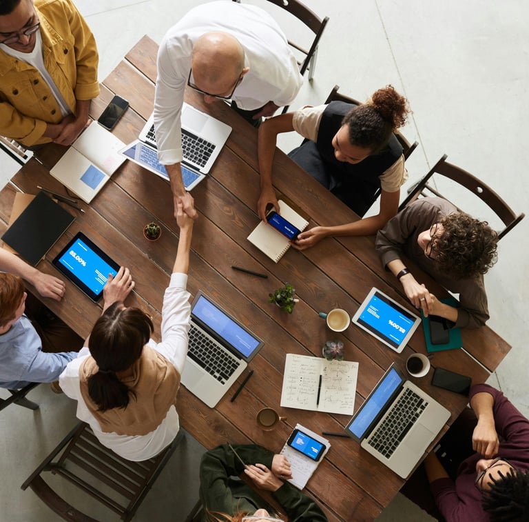 Clients and IT professionals meeting at a table with laptops and tablets, representing managed IT services and support