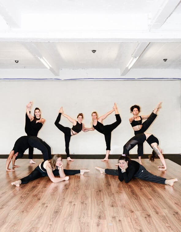 Acht mensen voeren verschillende acrobatische poses uit, waaronder brug, split en handstand in Gent