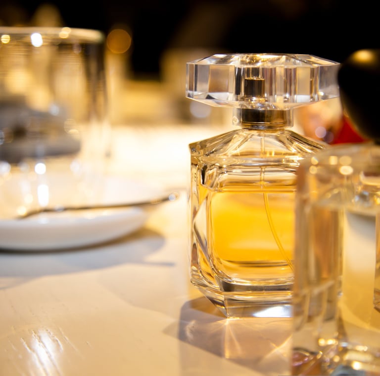 A glass perfume bottle with amber liquid and a faceted cap sits on a reflective surface