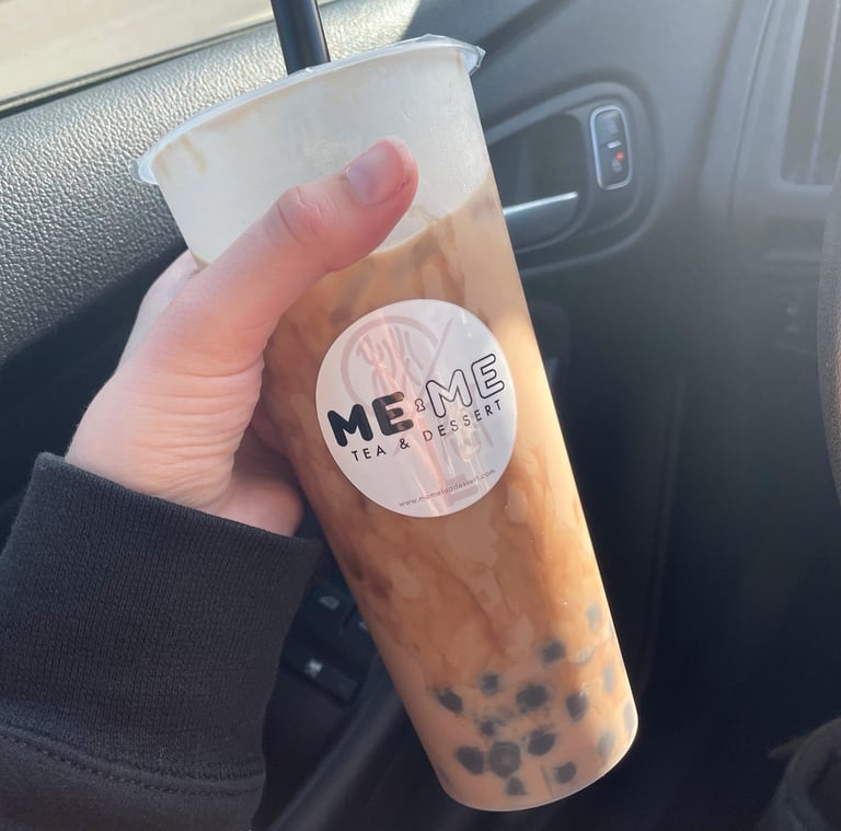 a person holding a cup of brown sugar milk tea with boba in a car