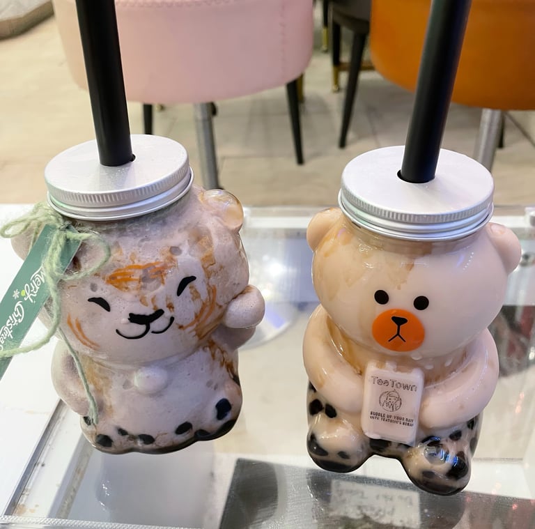 two cups of brown sugar milk tea with boba in animal-shaped cups on a table
