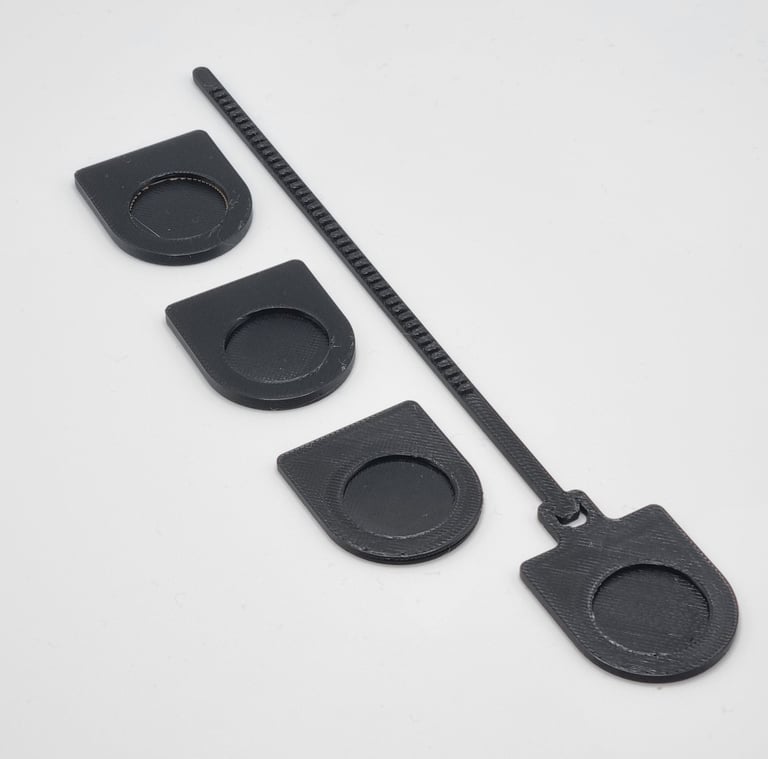 Black 3D printed cable management clips and a zip tie style organizer on a white background.